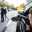 man in car secretly taking photos of man and woman walking across the street